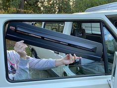 a woman is holding up the door handle on her car's side window to open it