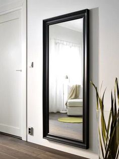 a large black mirror sitting on top of a wooden floor next to a white door