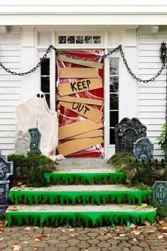 halloween decorations on the steps in front of a door with keep out signs and tombstones