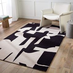 a black and white area rug with an abstract design on the floor next to a chair