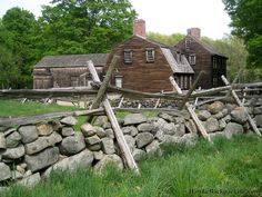 an old farm house with a stone wall and wooden fence