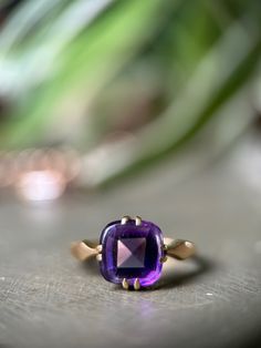 "This antique amethyst ring is utterly divine, with a rich solid 18ct gold band that really ignites that lavender-hued gemstone.  The amethyst is an unusual 'buff-top' cut, with a faceted bottom and smooth cabochon top, in the shape of a classic cushion cut. It is held securely in place by 4 double prongs on an 18ct gold setting.  The band is simple at the back, with just a touch of detail near the shoulders which taper to a point leading to that gorgeous stone. If you are intrigued by the world of spiritual healing, amethyst is thought to help ease sadness and alleviate stress. Sounds good to me!  Hallmarks: \"18CT\" tested as 18ct gold.  Condition: Very good condition. This ring still looks fab for an antique piece, the gold has turned buttery soft and still lovely and bright. There is a Gold Faceted Amethyst Ring, Faceted Purple Amethyst Ring For Formal Occasions, Formal Faceted Purple Amethyst Ring, Elegant Faceted Amethyst Ring In Yellow Gold, Faceted Amethyst Ring In Yellow Gold Fine Jewelry, Formal Faceted Amethyst Ring, Purple Faceted Ring For Formal Occasions, Formal Faceted Purple Ring, Formal Purple Faceted Ring