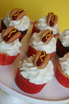 cupcakes with frosting and hot dogs on them are sitting on a plate