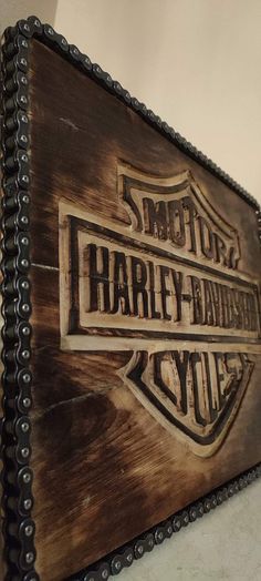 the harley davidson logo is painted on an old wooden sign with chains hanging from it's sides