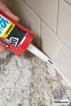 a hand holding a toothbrush in front of a bathroom counter with tile on it