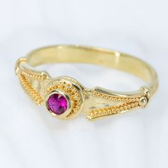 This 18K granulated gold ring adds a classic touch to any ensemble. A simple and elegant design combined with a timeless look make this Ruby Classical Ring the perfect accessory for a variety of occasions. 18K gold granulated ring with beautiful 0.22ct ruby. Currently a size 8, but each ring comes with free sizing and FREE SHIPPING! Unsure what ring size you are? It's always best to be sized by a professional jeweler, but if that is not available, you can use our special Ring Sizing Chart. Formal Gold Stackable Ruby Rings, Gold Ruby Ring With Bezel Setting, Heirloom Style, 22k Yellow Gold Ruby Ring For Anniversary, Heirloom Gold Ruby Ring With Bezel Setting, Gold Ruby Ring With Accent Stones For Promise, 22k Gold Ruby Ring For Anniversary, Elegant 22k Gold Emerald Ring, Gold Stackable Rings With Ruby Bezel Setting, Gold Ruby Ring With Accent Stones