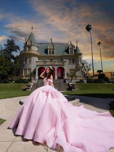 a woman in a pink dress is posing for a photo outside a castle like building