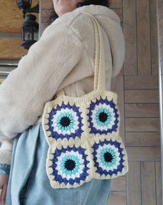 a woman is holding a crocheted purse