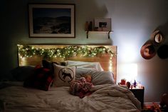 a small child is sleeping on a bed with christmas lights strung over the headboard