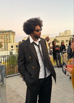 a man in a suit and tie standing on a balcony with other people looking at him