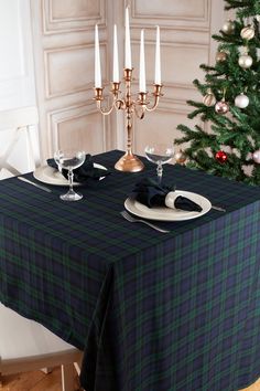 the table is set for two with place settings and silverware on it, next to a christmas tree