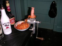 a bowl of noodles is being grated with a meat grinder and bottles are in the background