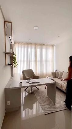 a woman standing in front of a living room with a couch and table next to it