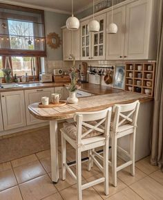 a kitchen with a table and chairs in the middle of it, next to a window