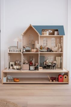 a doll house with furniture and accessories on the floor in front of a white wall