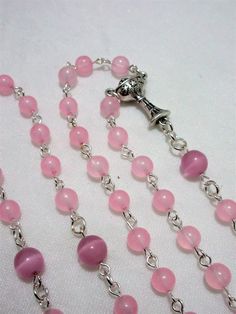 This pink First Communion rosary for girls is made with 6mm pale pink agate rounds and 8mm matte pink cat's eye beads. It measures about 27 inches around the body and has a 5 inch cross drop. The crucifix and the chalice are Italian made oxidized silver. I hand turned the silver plated wires. This rosary will be slipped into a velvet bag and shipped in a bubble mailer. Pink Rosary With 8mm Round Beads, Pink Beaded Rosary With Round Beads, Pink Rosary With Round Beads For First Communion, Pink Rosary For First Communion, Handmade Pink Rosary With Round Beads, Pink Beaded Rosary, Catholic Communion, Catholic Rosary, Matte Pink