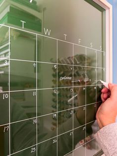 a person writing on a blackboard in front of a calendar