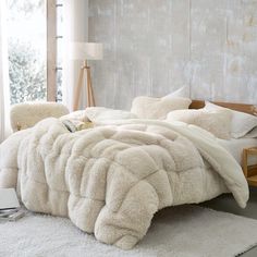 a bed with white fluffy blankets and pillows