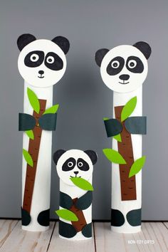 two pandas are standing next to each other with green leaves on their arms and legs