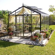 a glass house sitting on top of a lush green field next to a garden filled with flowers