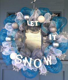 a blue wreath that says let it snow on the front door with silver and white ornaments