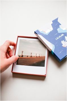 a person holding an open photo album in front of a white table with a blue box