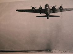 an old airplane flying over the ocean on a foggy day in black and white