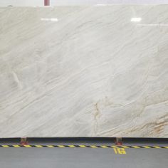 a large white marble slab with yellow lines on the floor and two men standing in front of it