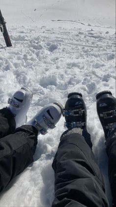 two people with skis and snow shoes in the snow, looking down at them