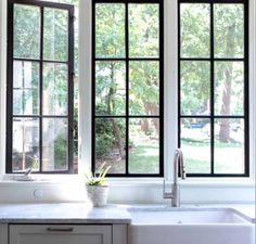 a kitchen sink sitting under two large windows