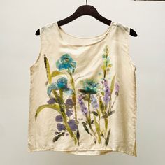 Introducing our exquisite hand-painted blue wildflowers on fine white silk blouse. This one-of-a-kind top is a true masterpiece, combining art and fashion in a stunning way. 🎨 Art you can wear: Each blouse is meticulously hand-painted with delicate wildflowers and leaves, creating a truly unique and artistic design that sets it apart from mass-produced clothing. 🌸 Hand-Painted wildflowers & leaves: The intricate details of the hand-painted blue wildflowers and leaves make this blouse a wearable work of art. The beautiful design adds a touch of nature's beauty to your wardrobe. 🌱 Light soft pure silk: Crafted from the softest silk, this blouse offers a luxurious and comfortable feel against your skin. The light and breathable fabric make it perfect for any season. 🌾 Easy to wear relaxed Artistic Floral Print Tops For Spring, White Silk Summer Tops, White Hand Painted Top For Summer, Silk Summer Tops With Floral Embroidery, Blue Watercolor Print Tops For Spring, Blue Watercolor Print Top For Spring, Blue Watercolor Print Tops For Summer, Painted Blouse, Blue Wild Flowers