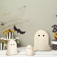 three wooden ghost figurines sitting on top of a white mantle next to halloween decorations