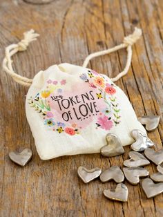 a small bag filled with silver hearts on top of a wooden table