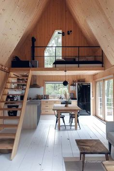 a loft with wooden walls and stairs leading up to the upper floor, along with an open kitchen area