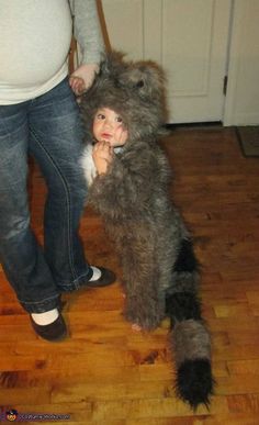 a woman standing next to a child dressed as a dog and holding the leg of a stuffed animal