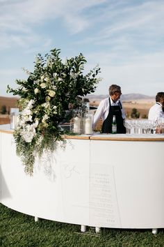 two people standing at a bar with flowers on it