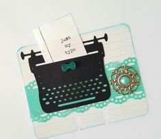 a typewriter and brooch sitting on top of a piece of paper that says just my type