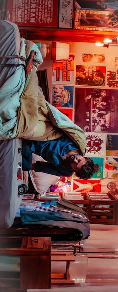 a man laying on top of a piece of luggage in a room filled with posters