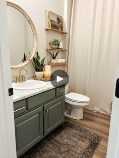 a white toilet sitting next to a bathroom sink under a mirror on top of a wooden floor