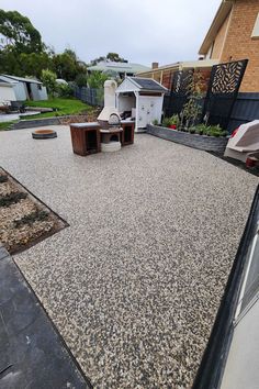 an outdoor area with gravel and wooden furniture