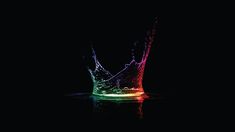 a rainbow colored water splashing on top of a black surface