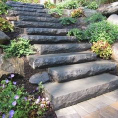 stone steps leading up to the top of a hill with flowers growing on each side