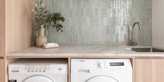 a washer and dryer sitting in a kitchen next to a counter with a potted plant on it