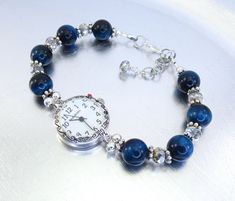 "This is an elegant bracelet watch that will compliment many items in your wardrobe. Made with beautiful 10mm blue Tiger Eye stones that are surrounded by silver tone spacers, and 6mm faceted rondelle vitrail crystal glass that adds magnificent sparkle and shine.  It is strung on super strong Beadalon 49 strand wire, has a lobster claw clasp with a 1\" extender chain. Choose your size: Small - 5 1/2\"- 6 1/4\" Medium - 6 1/4\" - 7\" Large - 7 1/4\" - 8\" X-Large - 8\"- 8 3/4\" If you are interes Blue Watches With Bracelet Strap As Gift, Elegant Blue Watch With Bracelet Strap, Timeless Blue Diamond Watch With Chronometer, Elegant Blue Glass Bracelets, Craft Bracelets, Beaded Watches Bracelet, Blue Tiger Eye Stone, Beaded Watches, Blue Tiger Eye