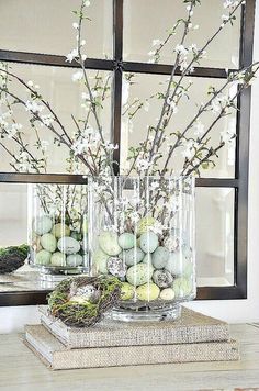 two vases filled with flowers and eggs sitting on top of a table next to a mirror