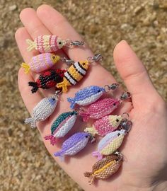 a hand holding several small knitted fish keychains in it's palm