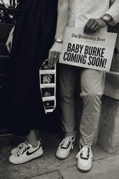 two people standing next to each other holding signs that say baby burk coming soon