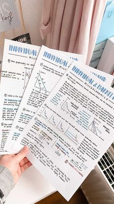 two sheets of paper are held up in front of a computer keyboard and other items