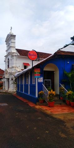 a blue and white building with a red sign on it's front door in the middle of town