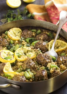 a pot filled with meat and vegetables on top of a blue tablecloth next to lemons